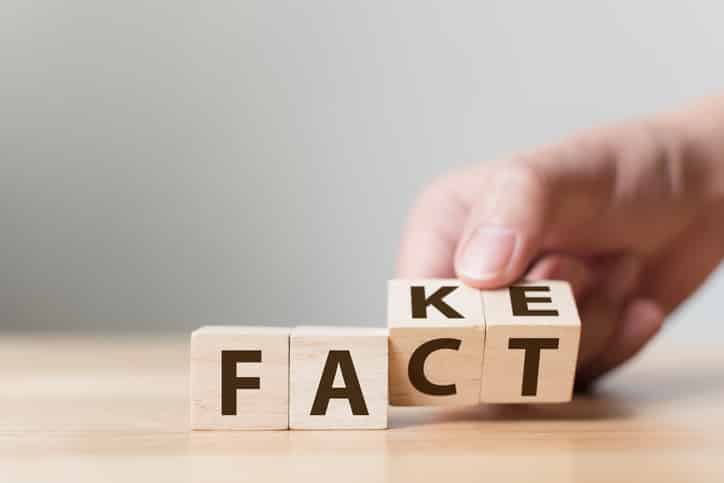 Hand turning blocks to change "FAKE" to "FACT".  Truth vs. falsehood concept.