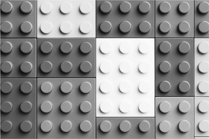 Here's some alt text options for the image:
**Option 1 (Shortest):**
>Grayscale LEGO bricks in a grid pattern.
**Option 2 (More descriptive):**
>A grid of grayscale LEGO-like blocks, with a central white section.
**Option 3 (If context is important):**
>Design concept: Grayscale LEGO bricks arranged in a grid showing variations in color.